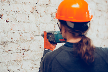 Image showing Close up of hands of repairman, professional builder working indoors, drills a wall