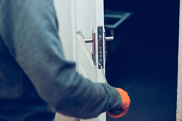 Image showing Close up of handyman repair the door lock in the room, fixing lock with screwdriver in the home or office