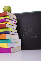 Image showing apple over a stack of books next to a chalkboard 