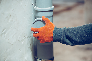 Image showing Close up of hands of repairman, professional builder working indoors, installs sewer, duct