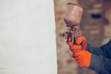 Image showing Close up of hands of repairman, professional builder working indoors, coloring the wall