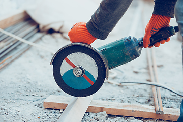 Image showing Close up of hands of repairman, professional builder working outdoors, cuts grinder