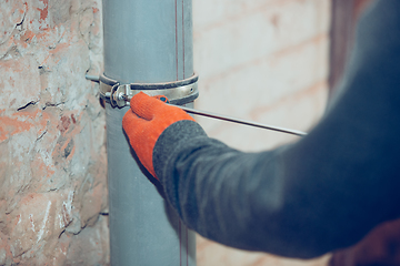 Image showing Close up of hands of repairman, professional builder working indoors, installs sewer, duct