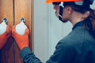 Image showing Electrician replace the lamp. Closeup of man repairing a lamp. Hazardous concept, high voltage, risk, wiring replacement, technician\'s occupation