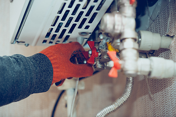 Image showing Male hand closes the wick of a gas bottle, heater, shuts off the flow