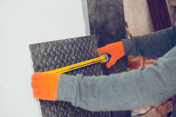 Image showing Close up of hands of repairman, professional builder working outdoors, measuring