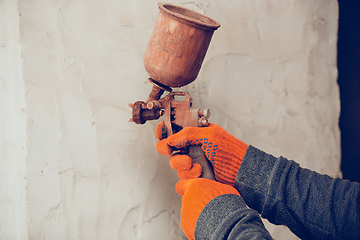 Image showing Close up of hands of repairman, professional builder working indoors, coloring the wall