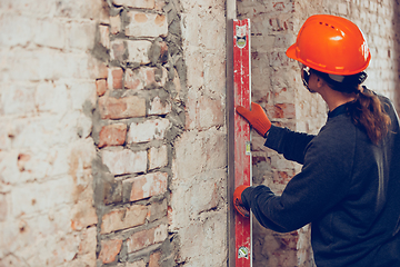 Image showing Close up of hands of repairman, professional builder working indoors, measuring the wall