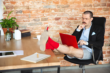 Image showing Young man without pants but in jacket working on a computer, laptop. Remote office during coronavirus, fun and comfortable work in underpants