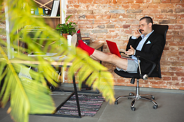 Image showing Young man without pants but in jacket working on a computer, laptop. Remote office during coronavirus, fun and comfortable work in underpants