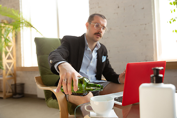 Image showing Young man without pants but in jacket working on a computer, laptop. Remote office during coronavirus, fun and comfortable work in underpants