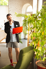 Image showing Young man without pants but in jacket working on a computer, laptop. Remote office during coronavirus, fun and comfortable work in underpants