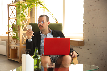 Image showing Young man without pants but in jacket working on a computer, laptop. Remote office during coronavirus, fun and comfortable work in underpants