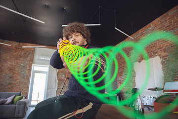 Image showing Portrait of millenial boy using retro toys, meeting things from the past and having fun, nostalgic, using rainbow spring toy