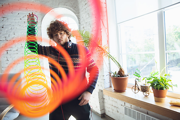 Image showing Portrait of millenial boy using retro toys, meeting things from the past and having fun, nostalgic, using rainbow spring toy