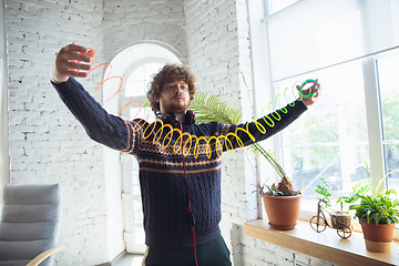 Image showing Portrait of millenial boy using retro toys, meeting things from the past and having fun, nostalgic, using rainbow spring toy