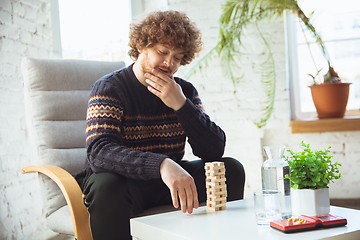 Image showing Portrait of millenial boy using retro toys, meeting things from the past and having fun, nostalgic, playing wooden constructor