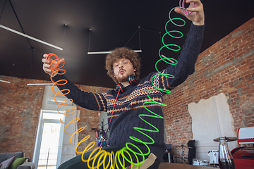 Image showing Portrait of millenial boy using retro toys, meeting things from the past and having fun, nostalgic, using rainbow spring toy