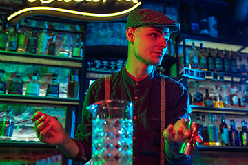 Image showing Barman proposing alcoholic cocktails, shots, beverages to guest in multicolored neon light