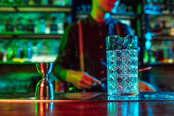 Image showing Close up of barman finishes preparation of alcoholic cocktail in multicolored neon light