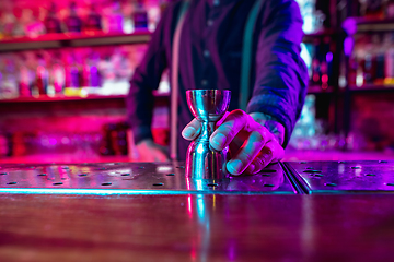 Image showing Close up of barman finishes preparation of alcoholic shot in multicolored neon light