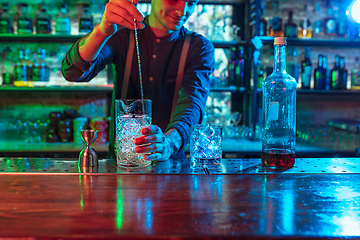 Image showing Close up of barman finishes preparation of alcoholic liquor and ice cocktail in multicolored neon light
