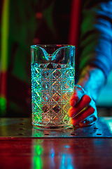 Image showing Close up of barman finishes preparation of alcoholic cocktail in multicolored neon light