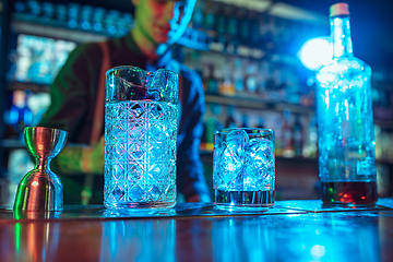 Image showing Close up of barman finishes preparation of alcoholic cocktail in multicolored neon light