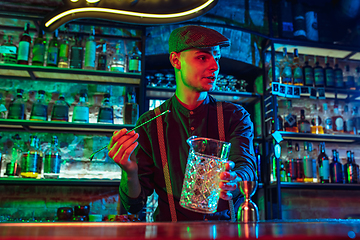 Image showing Barman proposing alcoholic cocktails, shots, beverages to guest in multicolored neon light