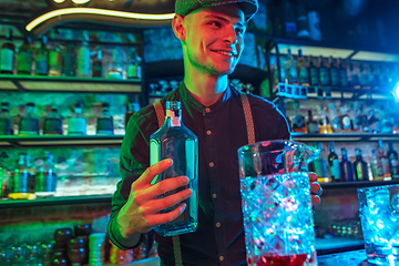 Image showing Barman proposing alcoholic cocktails, shots, beverages to guest in multicolored neon light