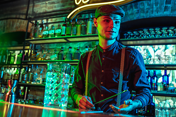 Image showing Barman proposing alcoholic cocktails, shots, beverages to guest in multicolored neon light