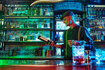 Image showing Barman preparing alcoholic cocktail in multicolored neon light