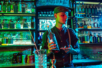 Image showing Barman proposing alcoholic cocktails, shots, beverages to guest in multicolored neon light