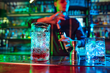 Image showing Close up of barman finishes preparation of alcoholic cocktail with shot in multicolored neon light