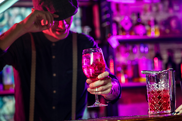 Image showing Barman proposing alcoholic cocktails, shots, beverages to guest in multicolored neon light