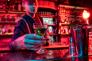 Image showing Barman proposing alcoholic cocktails, shots, beverages to guest in multicolored neon light