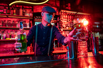 Image showing Barman proposing alcoholic cocktails, shots, beverages to guest in multicolored neon light