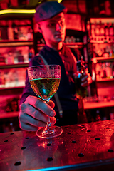 Image showing Barman proposing alcoholic cocktails, shots, beverages to guest in multicolored neon light