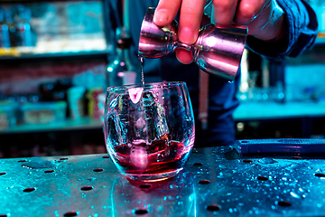 Image showing Close up of barman preparing of alcoholic cocktail with shot in multicolored neon light