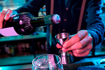 Image showing Close up of barman preparing of alcoholic cocktail with shot in multicolored neon light