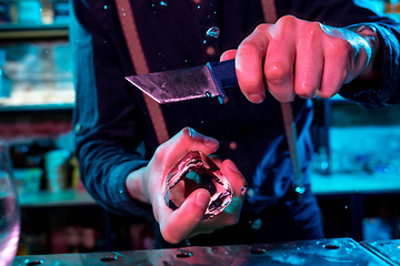 Image showing Close up of barman crushing a big piece of ice on the bar counter with a special bar equipment on it for a cocktail