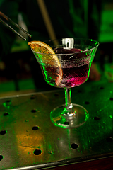 Image showing Close up of barman finishes preparation of alcoholic cocktail in multicolored neon light