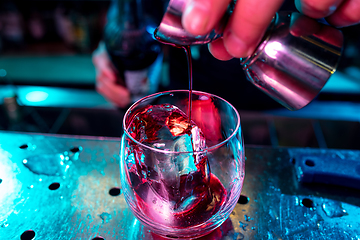 Image showing Close up of barman preparing of alcoholic cocktail with shot in multicolored neon light