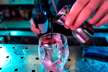 Image showing Close up of barman preparing of alcoholic cocktail with shot in multicolored neon light