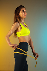 Image showing Fashion portrait of young fit and sportive woman with measurer on gradient background. Perfect body ready for summertime.