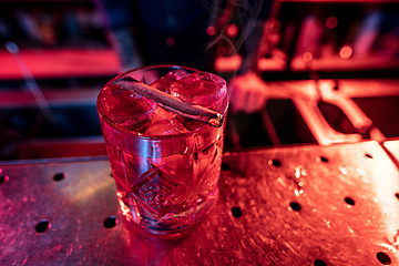 Image showing Close up of alcoholic cocktail, beverage, drink, glass full of ice in multicolored neon light