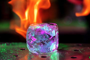 Image showing Close up big melting piece of ice on the bar counter in fireflames on it, preparation for a cocktail