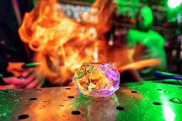 Image showing Close up big melting piece of ice on the bar counter in fireflames on it, preparation for a cocktail