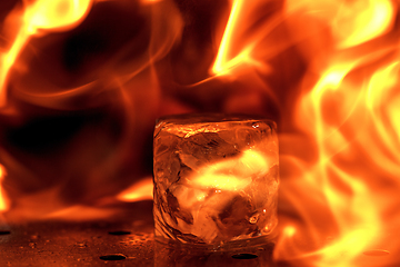 Image showing Close up big melting piece of ice on the bar counter in fireflames on it, preparation for a cocktail
