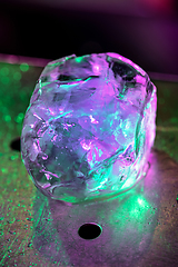 Image showing Close up big melting piece of ice on the bar counter in pink-green neon light on it, preparation for a cocktail